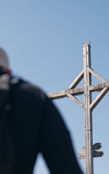 L'alpinista si affretta a raggiungere la croce di vetta | © RAW-Media